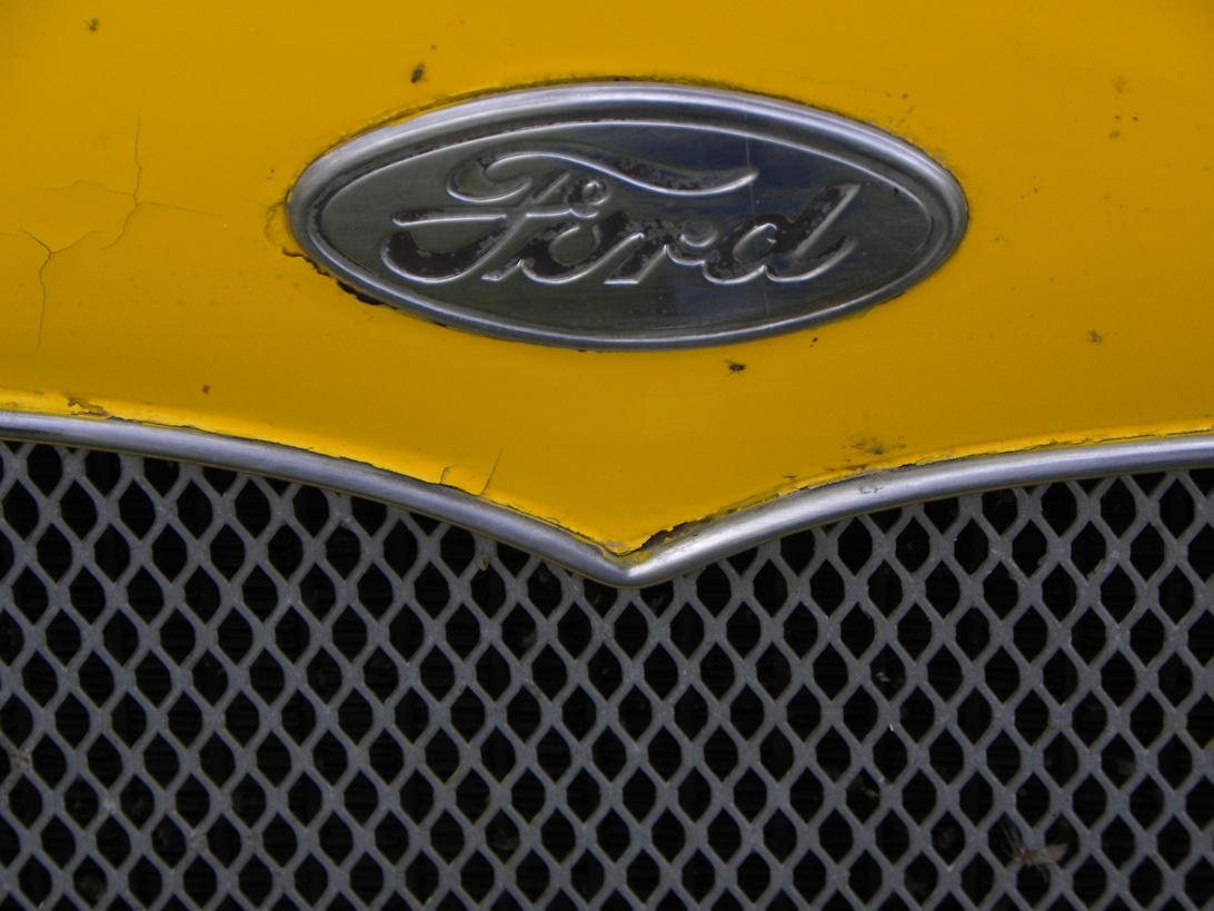 Närbild på en klassisk gul Ford-grill med det ikoniska ovala märket.